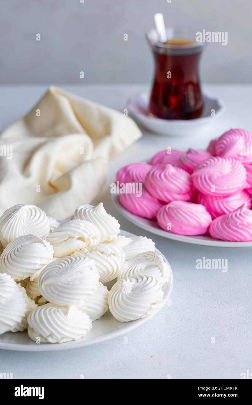 Piccole meringhe bianche e rosa in un piatto bianco. Scatto macro. Vista verticale Foto Stock