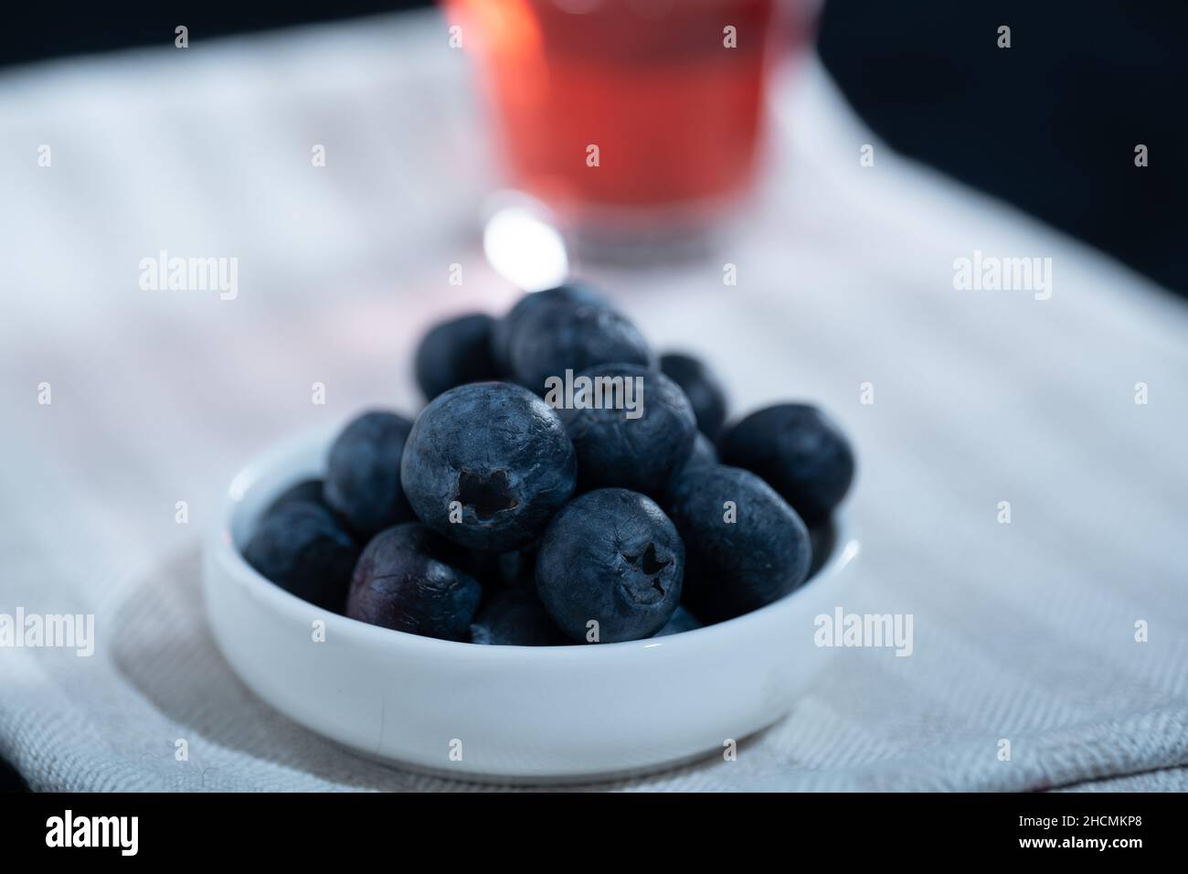 Helsinki / Finlandia - 27 DICEMBRE 2021: Primo piano di un vaso di mirtilli asciugamano da cucina. Un bicchiere di succo di mirtillo sullo sfondo. Foto Stock
