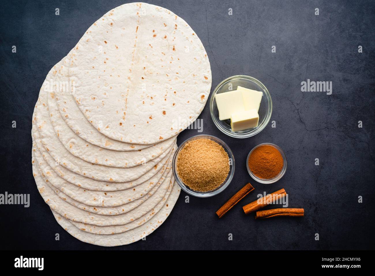 Vista dall'alto di Cinnamon Sugar Tortilla Chips ingredienti: Tortillas di farina, burro, zucchero di canna e cannella su sfondo scuro Foto Stock