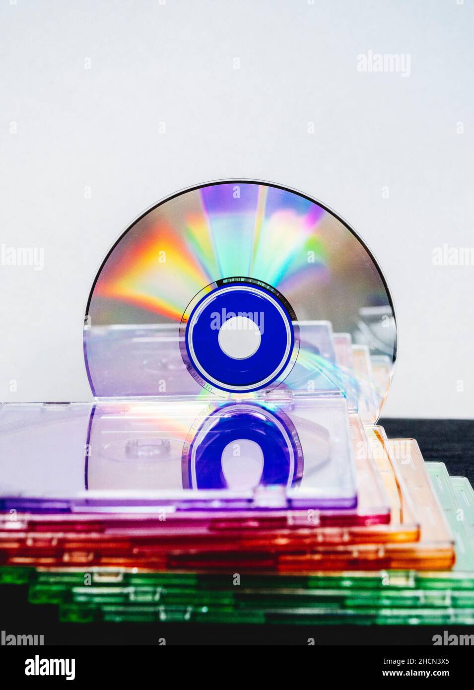 Disco compatto su sfondo bianco accanto ai supporti del vassoio per dischi multicolore Foto Stock