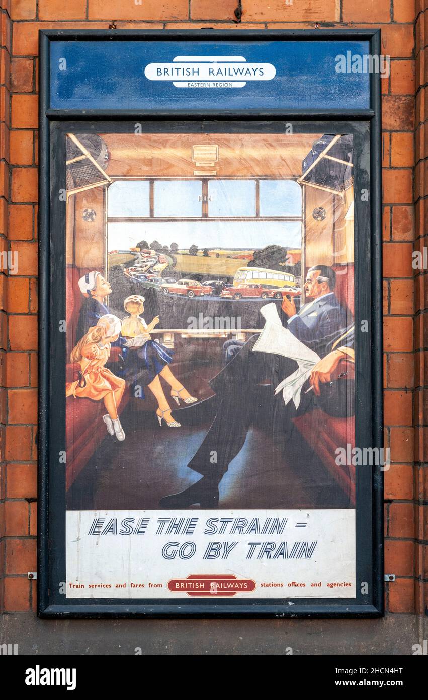 Un vecchio poster pubblicitario delle Ferrovie britanniche in mostra con il messaggio "Ease the strain - go by train" Foto Stock