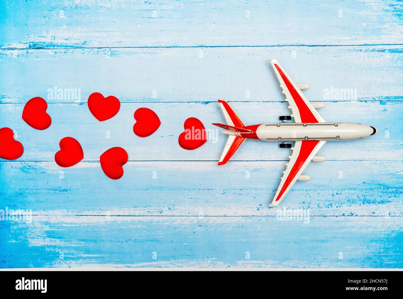 Giocattolo di aeroplano e cuore su sfondo di legno blu, concetto di viaggio d'amore Foto Stock