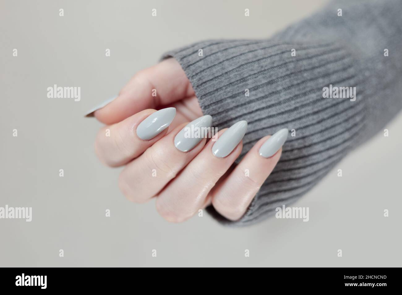 Mano femmina con unghie lunghe grigio chiaro manicure e una bottiglia di  smalto per unghie Foto stock - Alamy