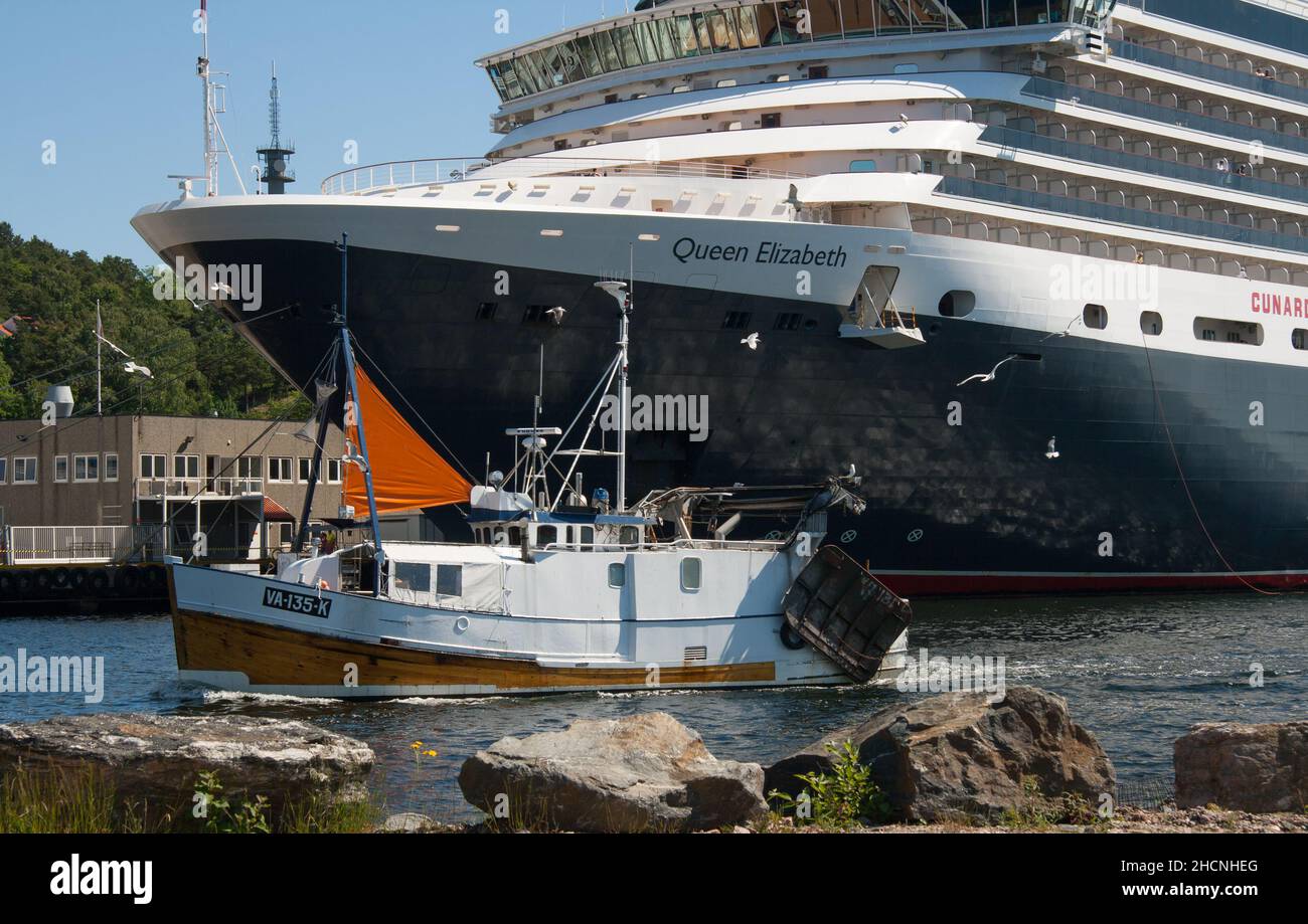 La nave da crociera Cunard Queen Elizabeth ormeggiata a Kristiansand, Norvegia. Nave da pesca locale che passa in primo piano. Foto Stock