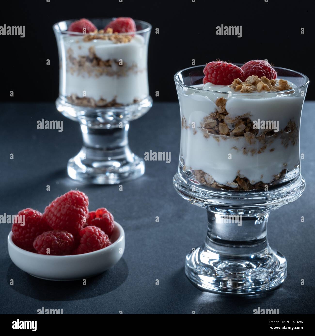 Helsinki / Finlandia - 30 DICEMBRE 2021: Due bicchieri di yogurt alla vaniglia con granola alla cannella e guarnizione di lampone Foto Stock