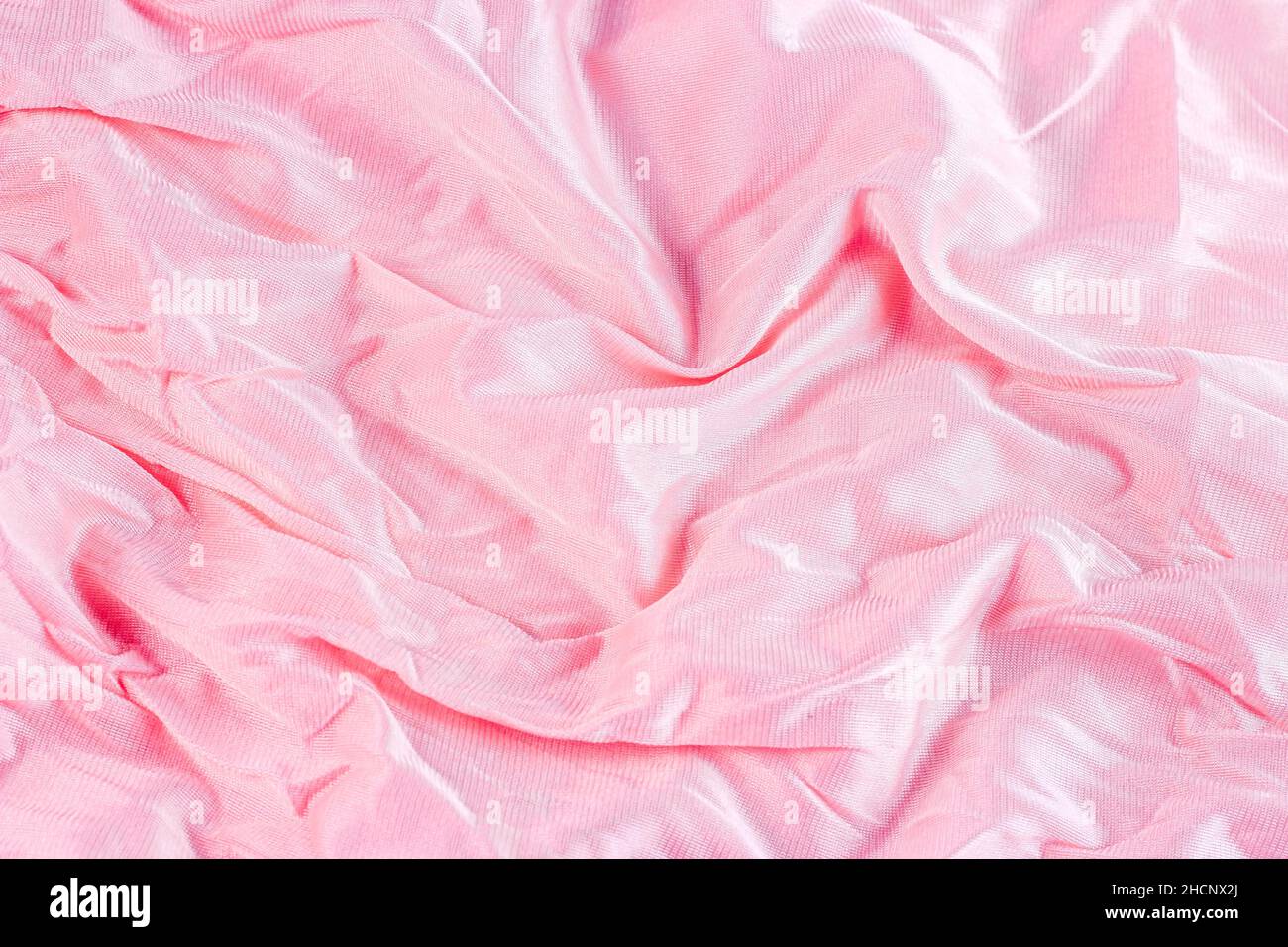 Colore rosa pastello chiaro nylon ondulato e motivo in poliammide come sfondo liscio testurizzato. Tendaggi in tessuto morbido di colore rosa pallido. Foto Stock