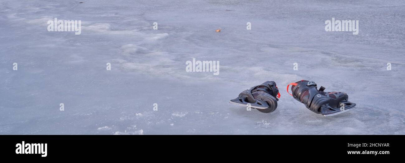 coppia di uomini pattina ghiaccio su un lago ghiacciato con riflessi al tramonto, banner web panoramico Foto Stock