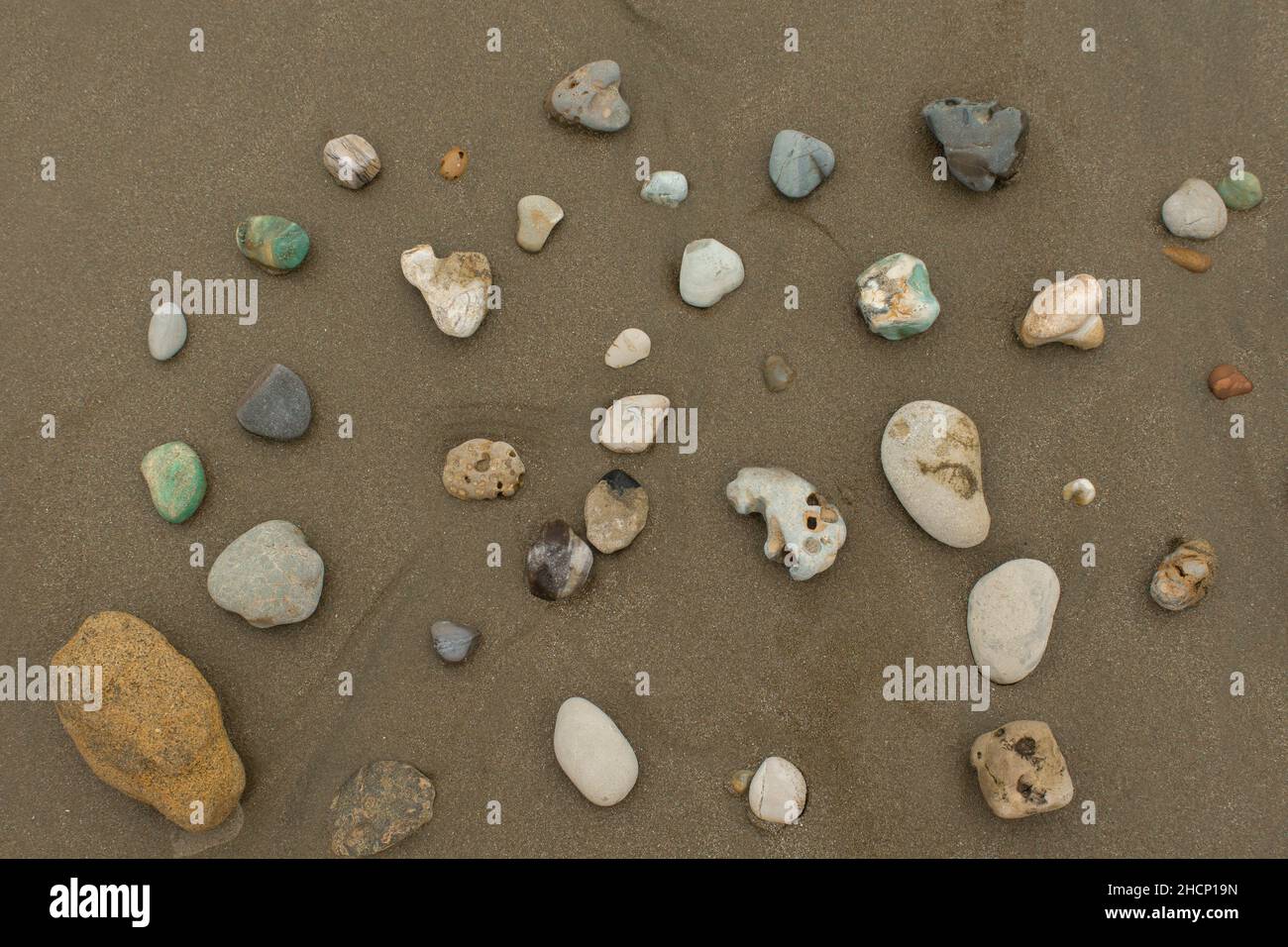 Vista dall'alto di un gruppo di pietre di diversi colori e strutture su una spiaggia vuota durante il giorno Foto Stock