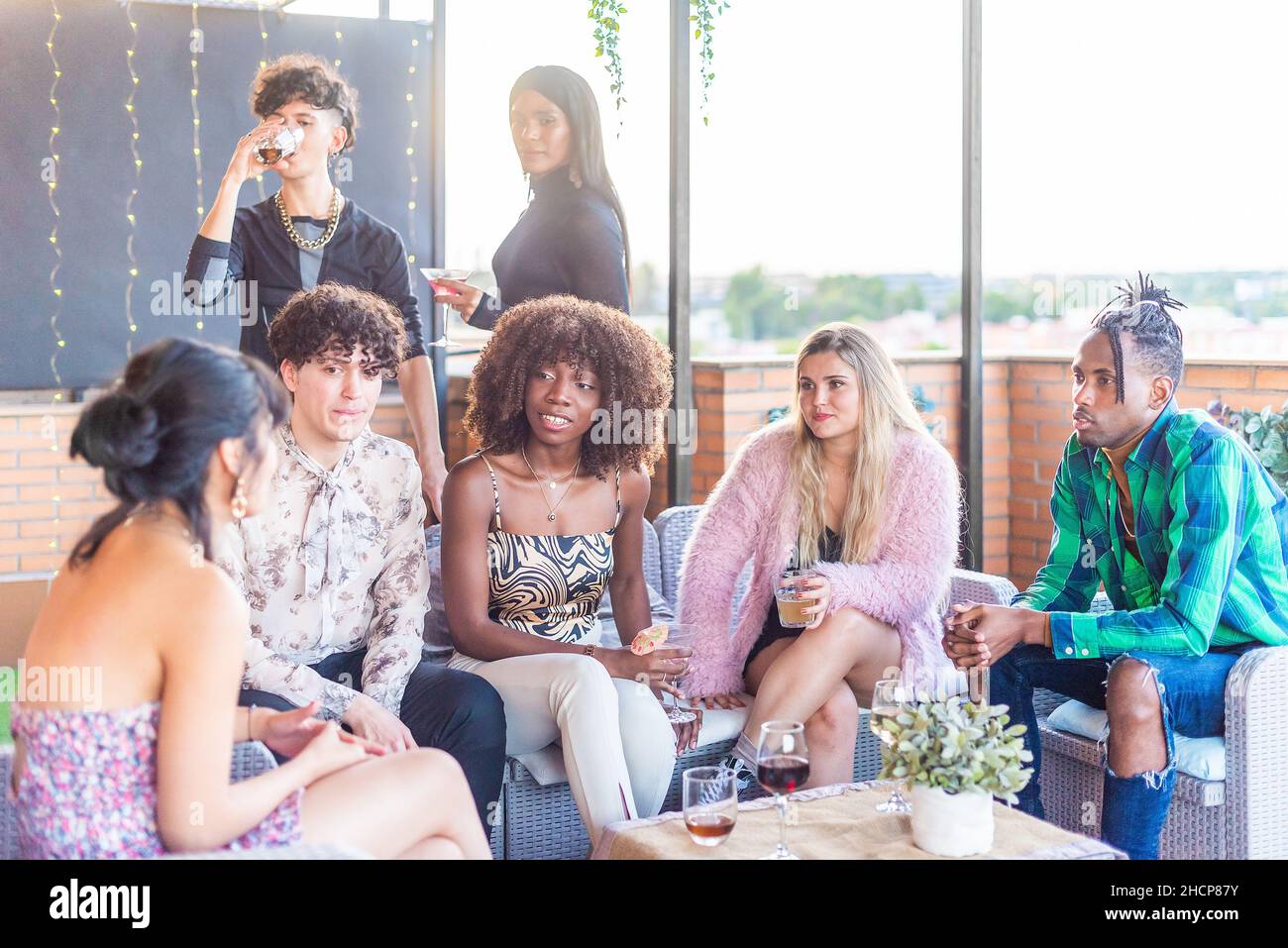 Gli amici chiacchierano sulla terrazza mentre bevono un drink Foto Stock