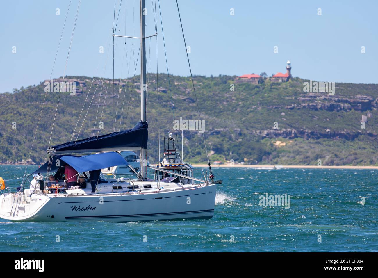 Barca a vela a Pittwater vicino Palm Beach sobborgo con barrenjoey promontorio e faro in lontananza, Sydney, NSW, Australia Foto Stock