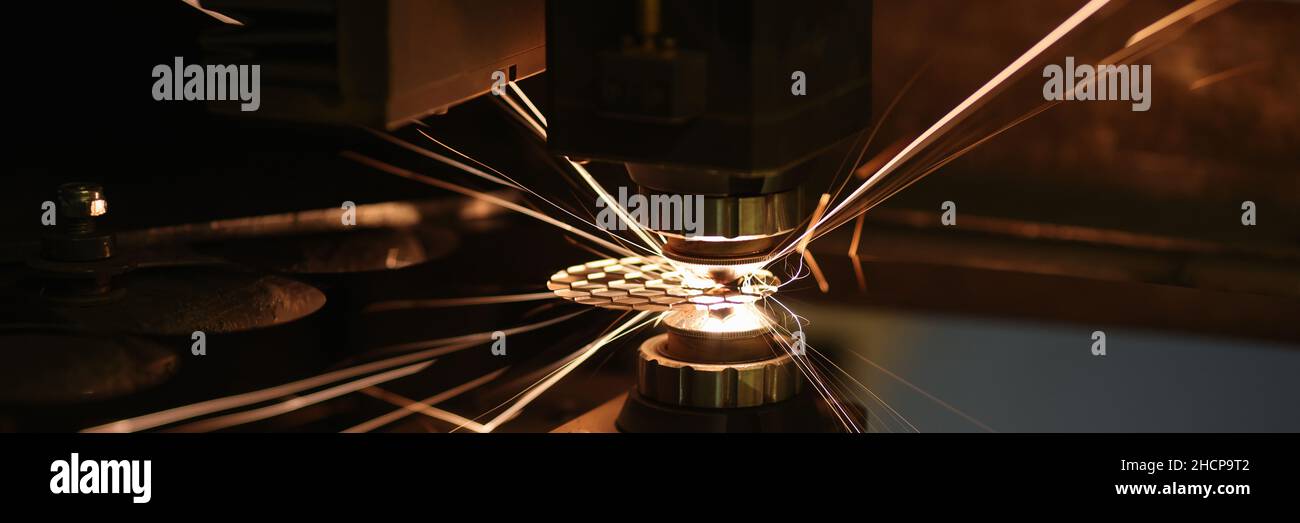 Scintille derivanti dal taglio laser automatico o dall'incisione di parti in primo piano Foto Stock