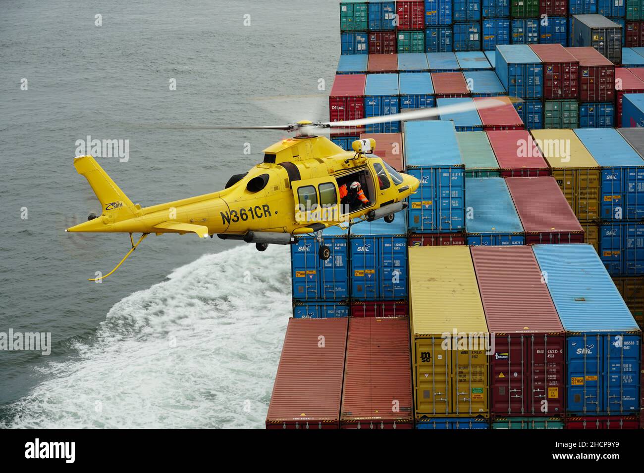 Volo in elicottero giallo con il pilota Columbia River Bar sui container. Foto Stock