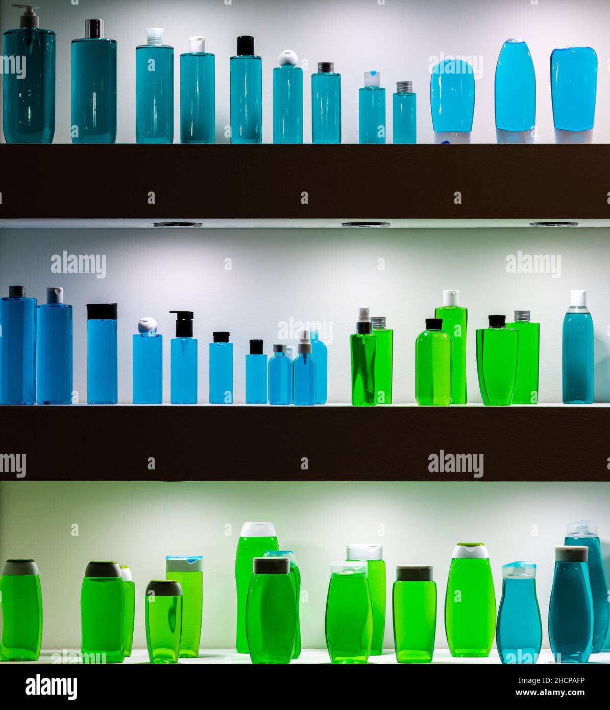 Molti flaconi colorati in plastica che si erigano sul ripiano iluminato. Foto scattata con luce artificiale. Foto Stock