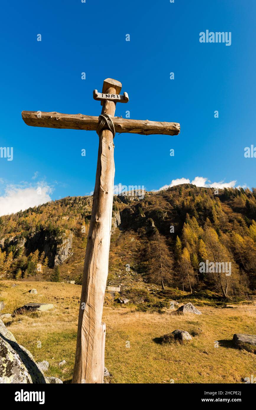 Antica croce di legno (tronchi di alberi) legata con corde con cielo blu e nuvole nel Parco Nazionale dell'Adamello Brenta. Trentino Alto Adige, Italia Foto Stock
