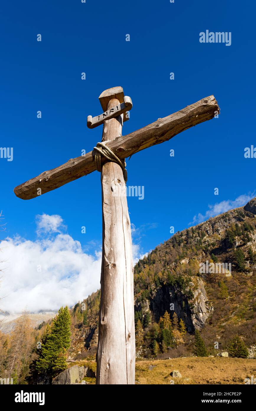 Antica croce di legno (tronchi di alberi) legata con corde con cielo blu e nuvole nel Parco Nazionale dell'Adamello Brenta. Trentino Alto Adige, Italia Foto Stock