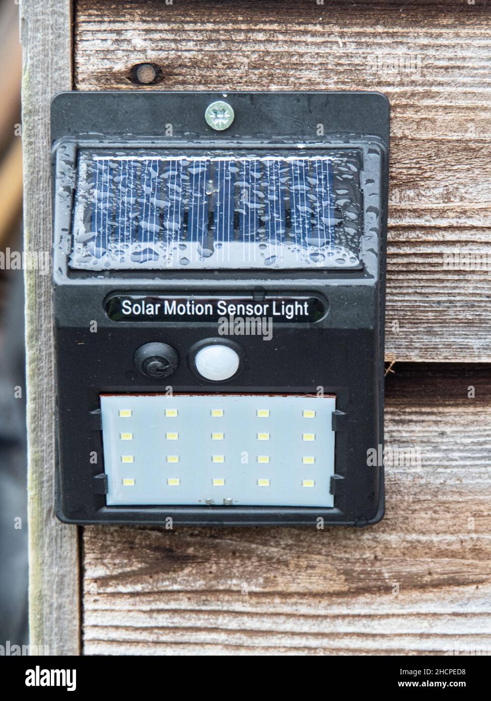 Una luce a sensore di movimento ad alimentazione solare con un array di LED fissato a un edificio in legno.l Foto Stock
