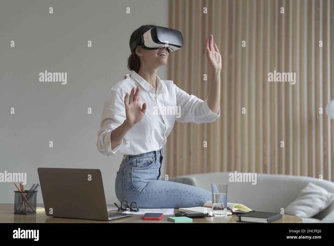 Ha impressionato la donna d'affari seduta sul tavolo da ufficio e utilizzando occhiali vr Foto Stock