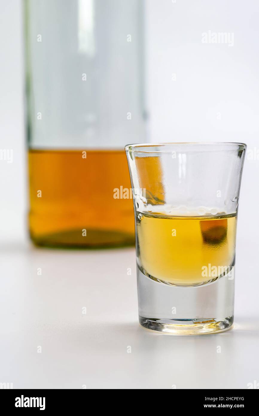 Bevanda alcolica in un bicchiere e bottiglia di brandy sul retro su tavola bianca. Di forte intossicazione alcolica. Il concetto di dipendenza da alcol. Alcoh Foto Stock