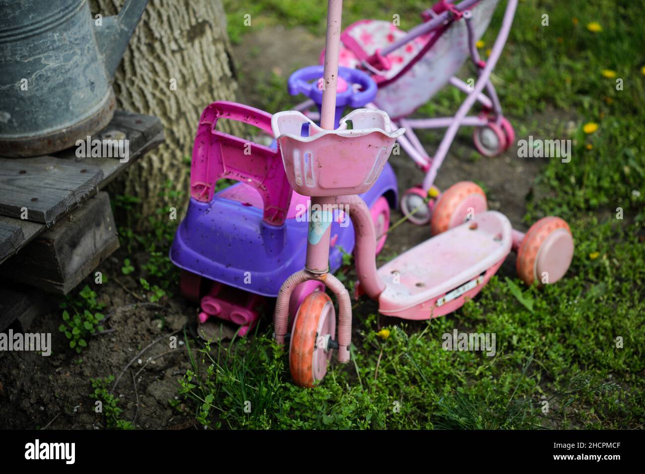 Profondità di campo bassa (fuoco selettivo) dettagli con giocattoli per bambina vecchia e sporca (scooter, passeggino) Foto Stock