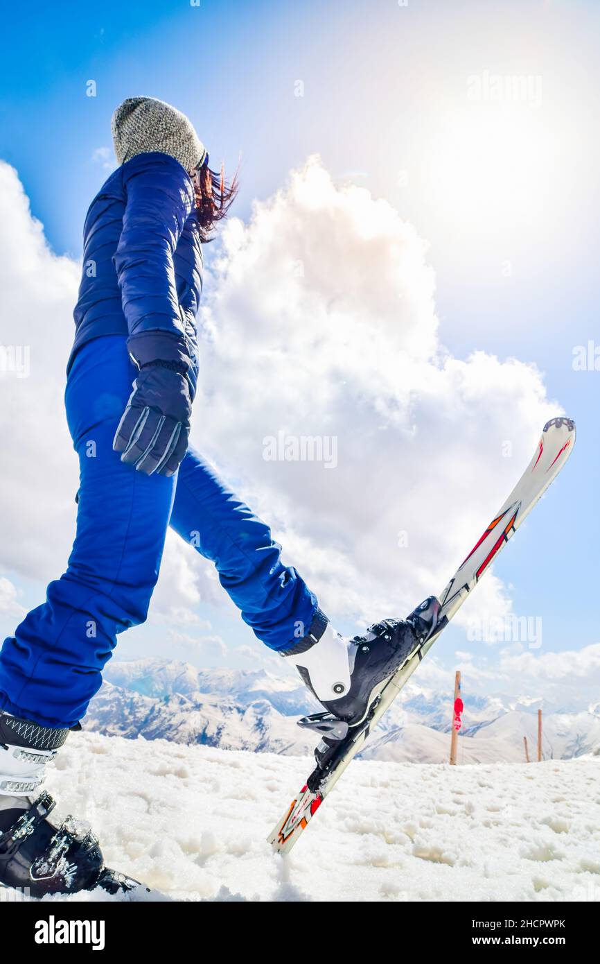 Giovane donna caucasica in abito blu guardare fino al cielo vuoto. Ski Holiday cattura i social media promo verticale sfondo verticale Foto Stock