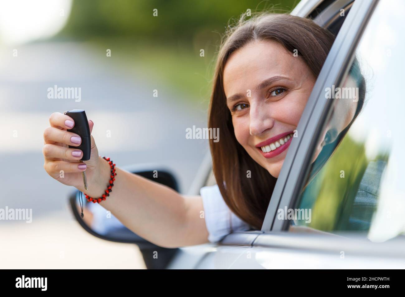 Giovane conducente donna con chiave in mano all'interno del noleggio o della nuova auto Foto Stock