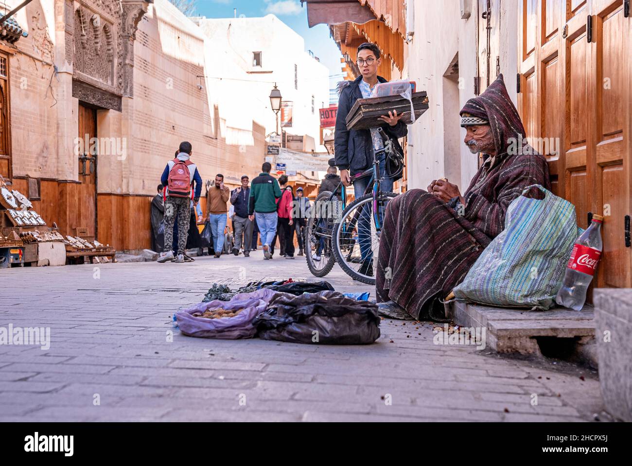 Scena di strada affollata con ciclista e senzatetto in primo piano Foto Stock