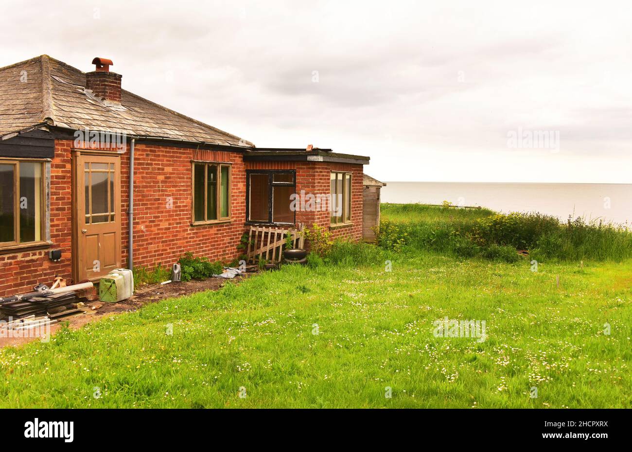 Casa abbandonata sul bordo di una scogliera minacciata dall'erosione costiera, Bacton, Norfolk, Inghilterra Foto Stock