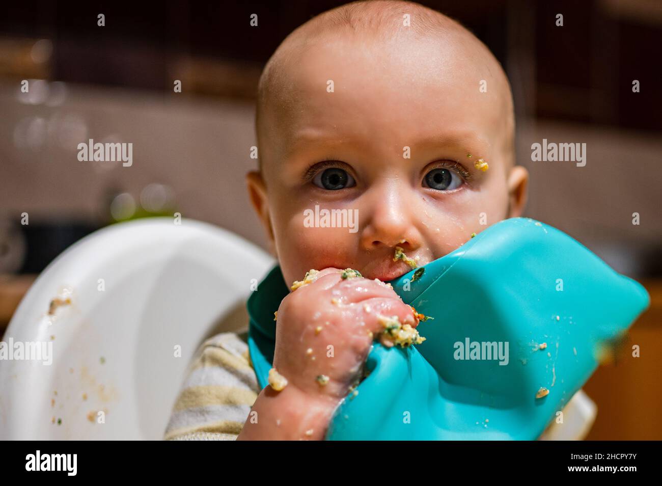 Un bambino piccolo sta imparando mangiare al tavolo Foto Stock