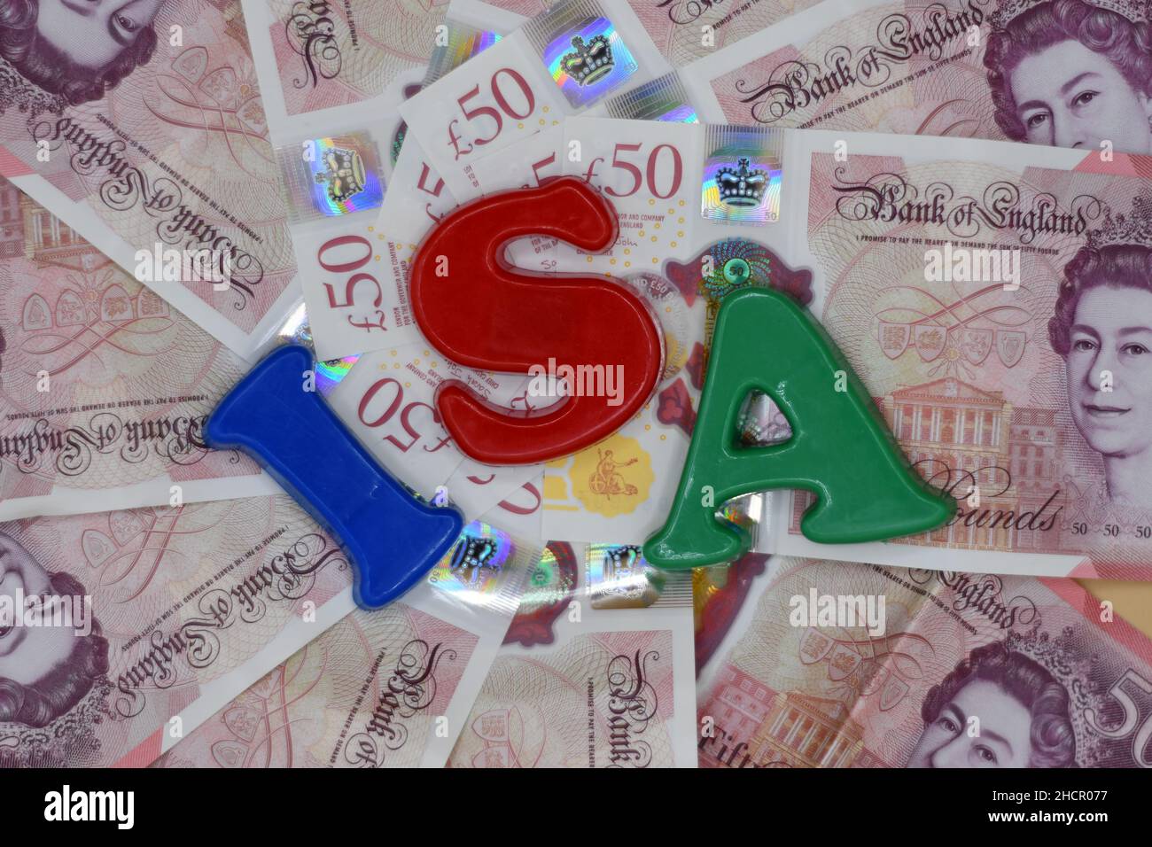 Lettere di plastica con l'abbreviazione ISA, concetto di conto di risparmio di investimento, su un letto di cinquanta banconote da £50 libbre, sterlina Foto Stock