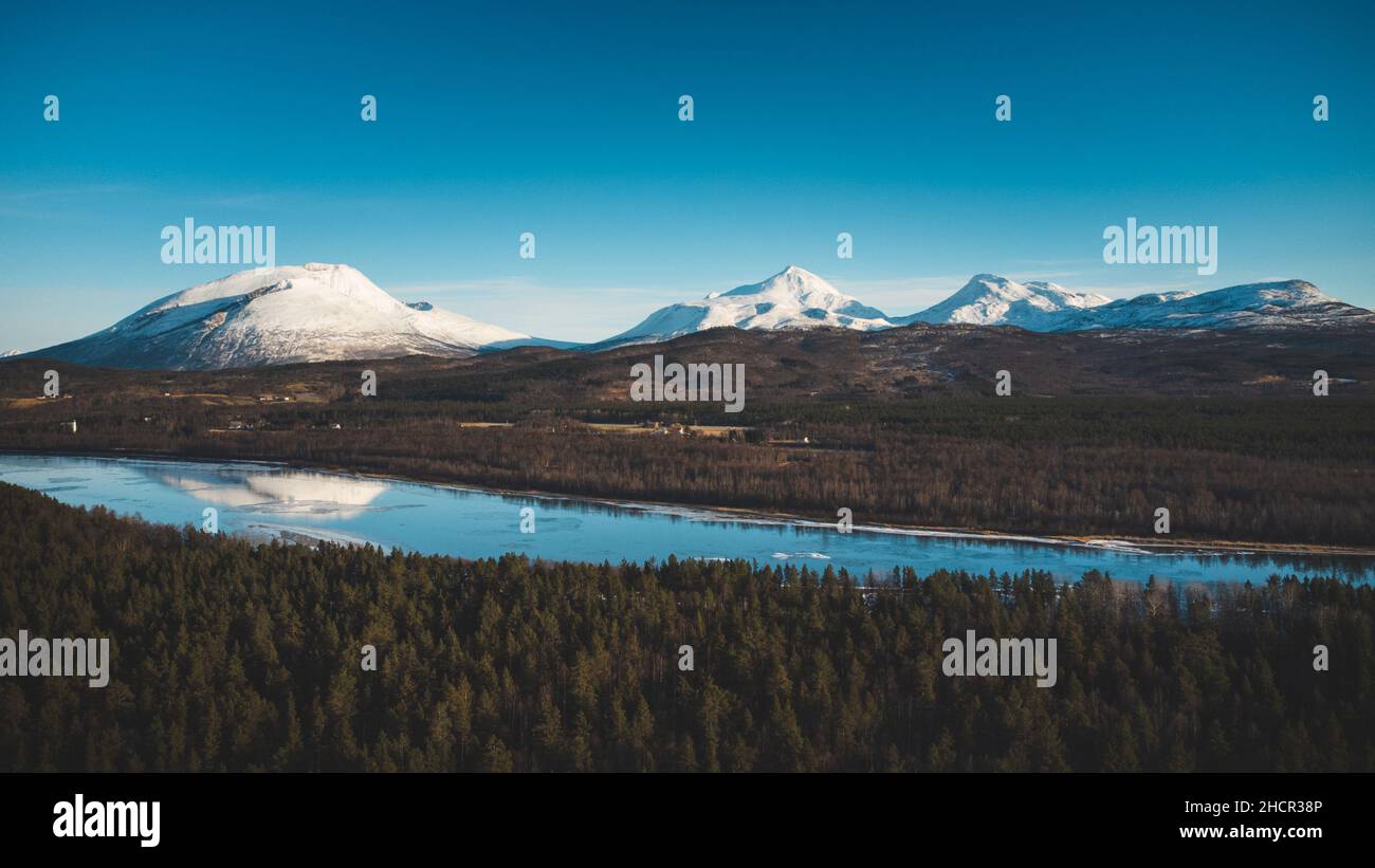 Vista sulla zona boschiva e sul fiume Malselva con un riflesso sulle colline innevate. Regione Finnmark, Nordland nel nord della Norvegia in bella Foto Stock