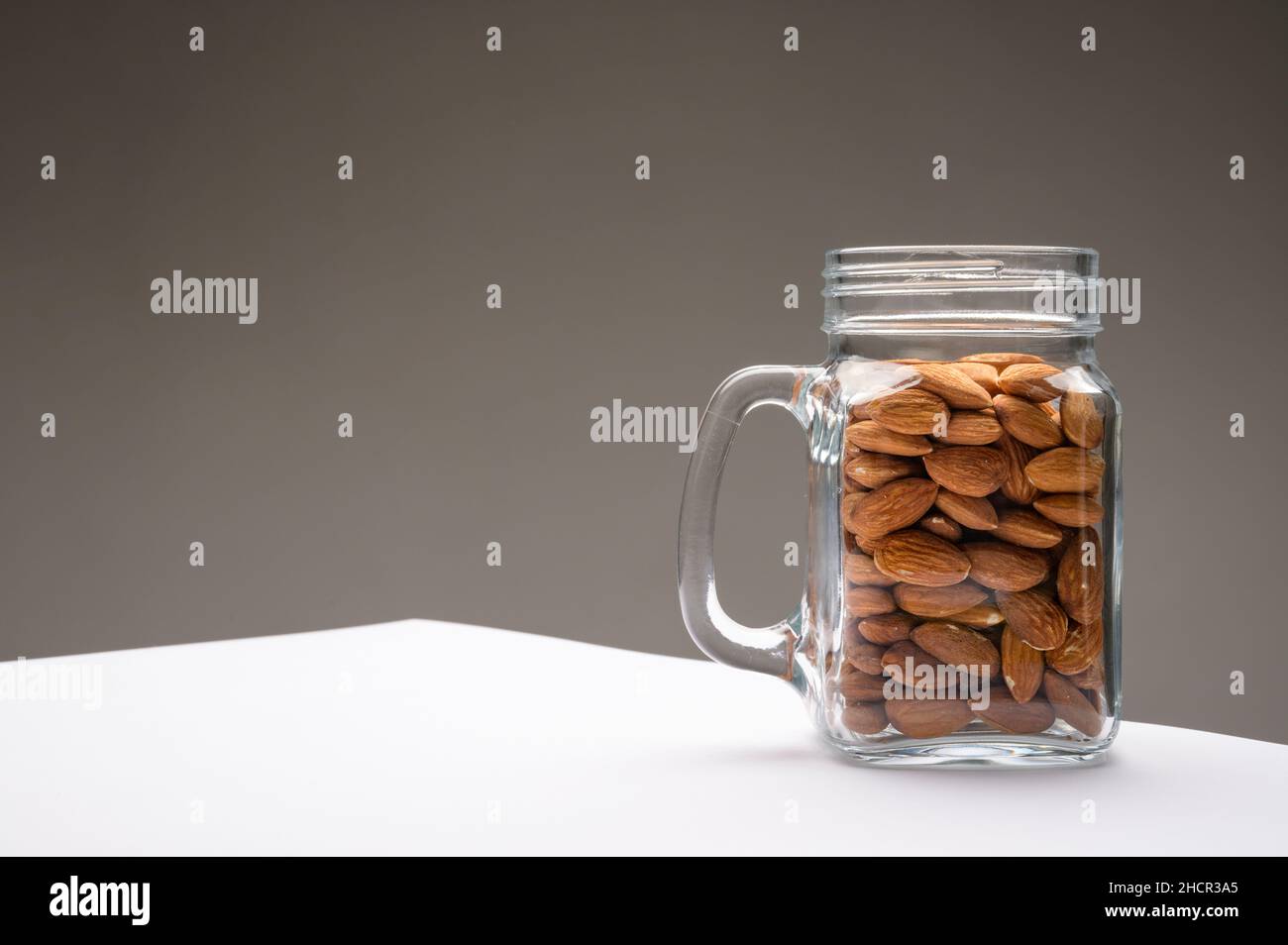 Vaso di vetro riempito con una varietà di nutrizione e snack sani e noci su uno sfondo scuro Foto Stock