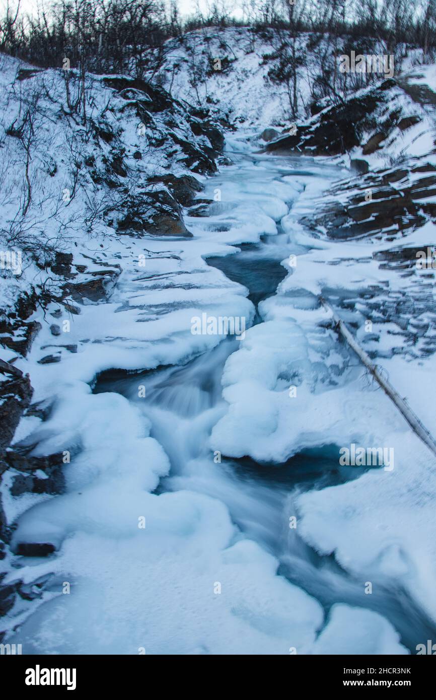 Fiume svedese coperto di neve e ghiaccio nel parco nazionale di abisko. Le ricchezze nascoste della lapponia svedese. Esposizione prolungata. Winter Wonderland. Foto Stock
