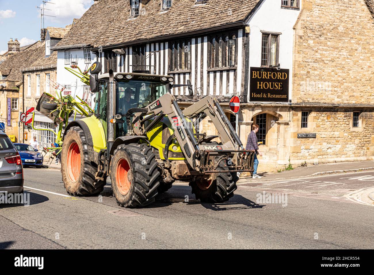 Grandi macchine agricole che guidano nella High Street della città Cotswold di Burford, Oxfordshire Regno Unito Foto Stock