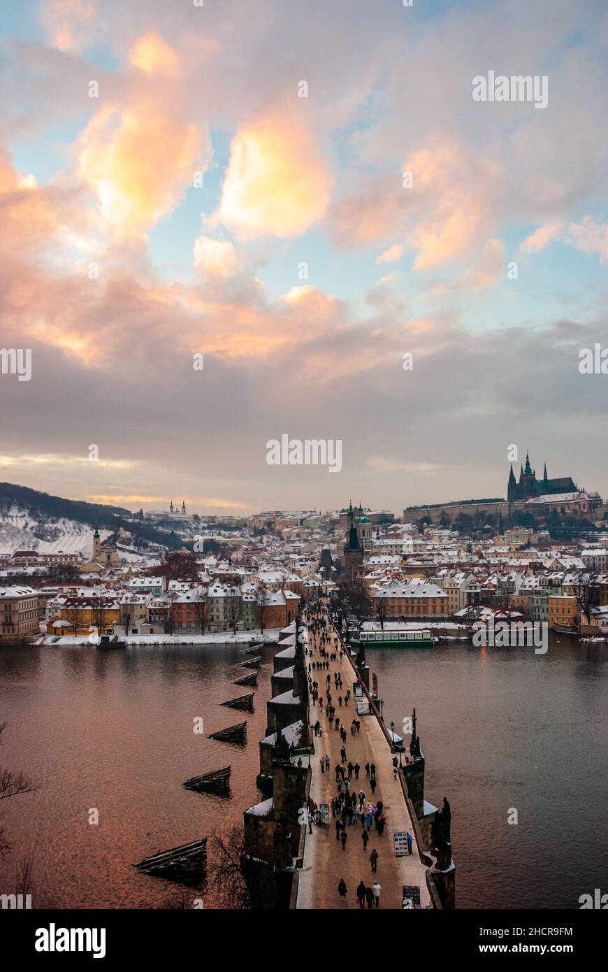 Europa, Repubblica Ceca, Praga. Ponte Carlo e fiume Moldava al tramonto dopo una nevicata. Castello di Praga e Cattedrale di San Vito in lontananza. Foto Stock