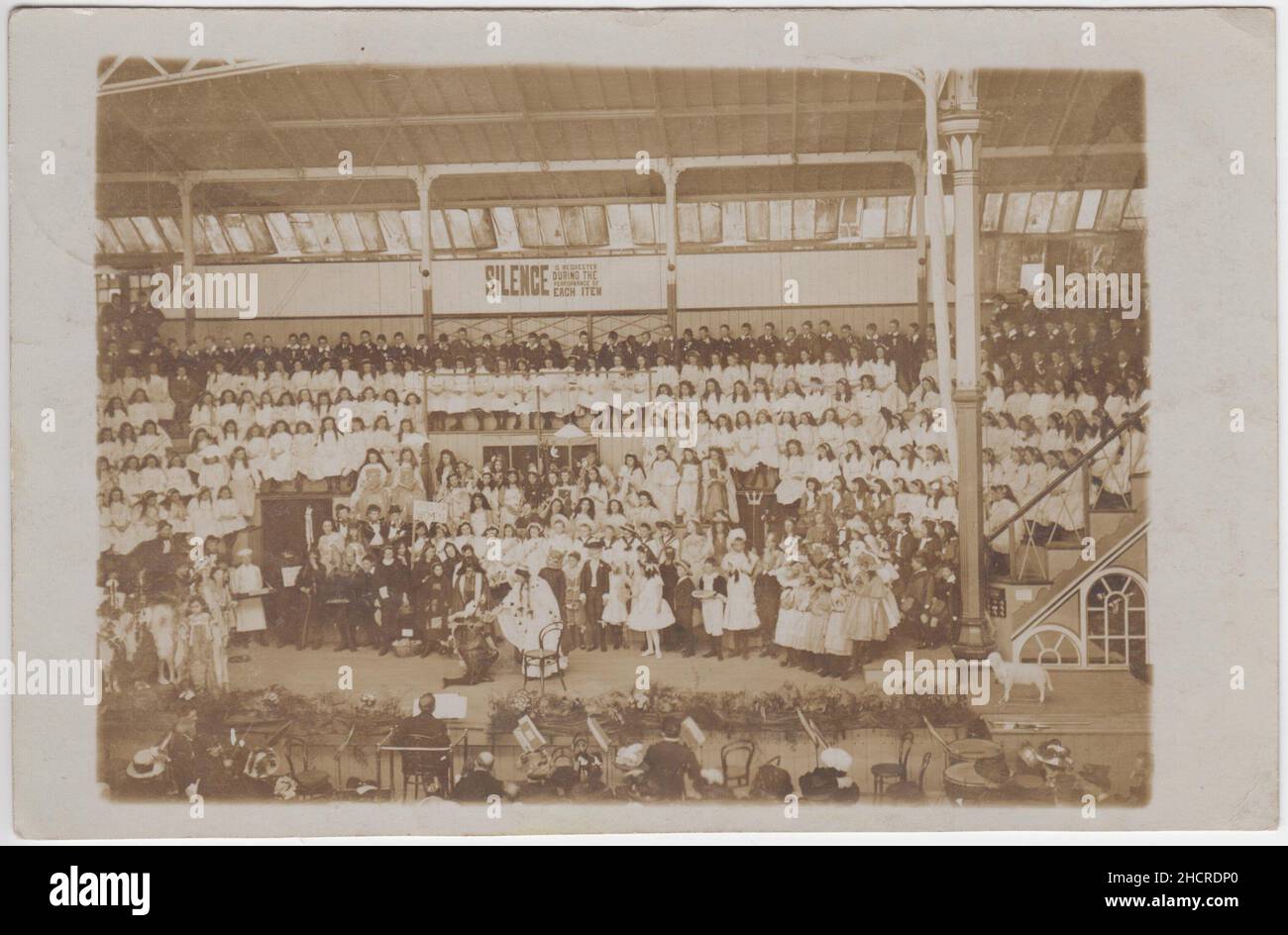 Bournemouth Winter Gardens Pavilion, 1909: Spettacolo di un grande gruppo di bambini, alcuni dei quali sono in abito fantasia (una ragazza sta portando un segno che dice 'voti per le donne'). Un agnello giocattolo sulle ruote è sul lato del palco Foto Stock