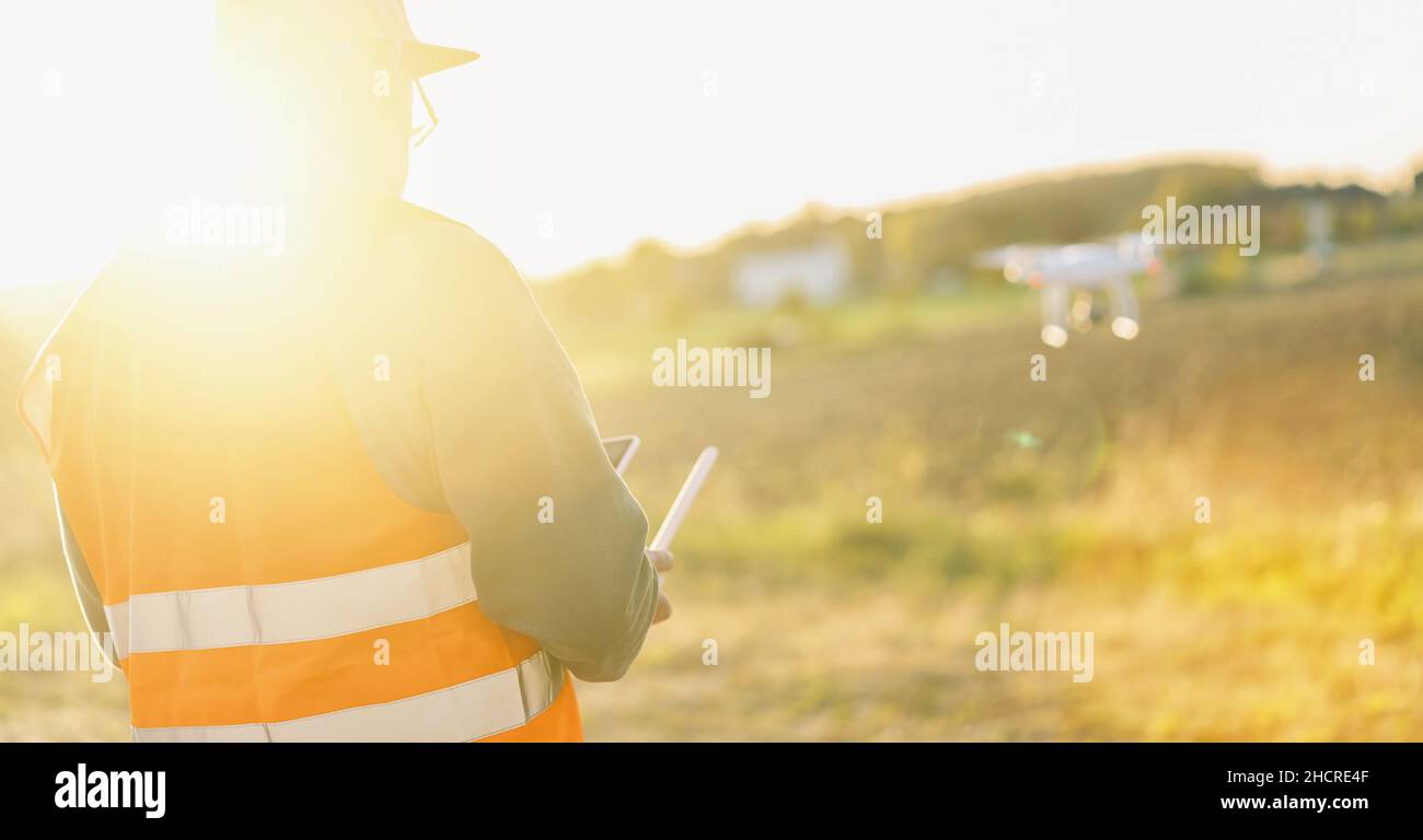 uomo che usa il drone al tramonto per foto e video Foto Stock