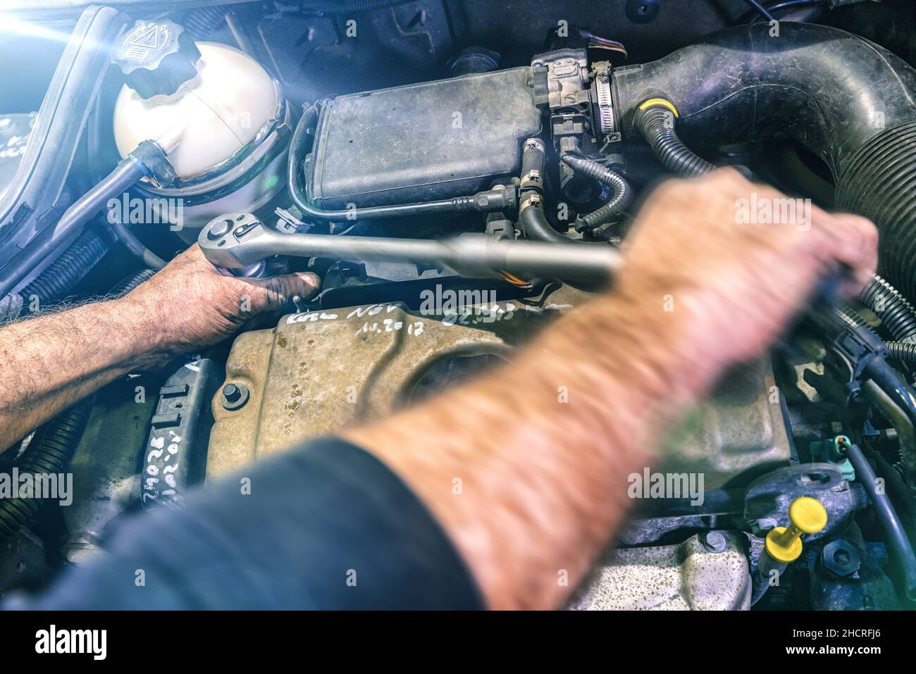 Meccanico automatico che lavora sul motore di un'auto in un garage meccanico. Servizio di riparazione. Primo piano autentico con sfocatura del movimento Foto Stock