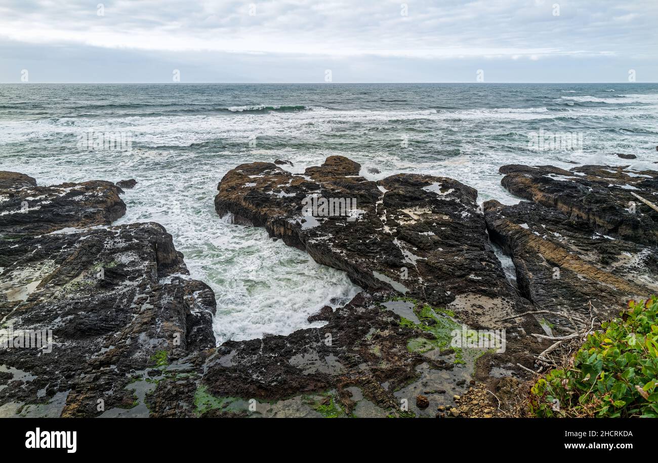 Le onde si lavano sopra le rocce costiere vicino a germogliare Horn Inlet presso Cape Perpetua Scenic Area in Oregon, USA Foto Stock