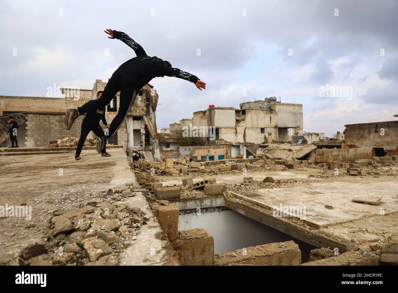 Idlib, Siria. 31st Dic 2021. Un giovane uomo dimostra la sua abilità di Parkour tra gli edifici distrutti dagli attacchi aerei russi. Credit: SOPA Images Limited/Alamy Live News Foto Stock