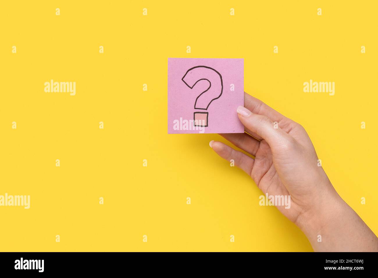 Donna che tiene una nota adesiva con punto interrogativo su sfondo giallo Foto Stock