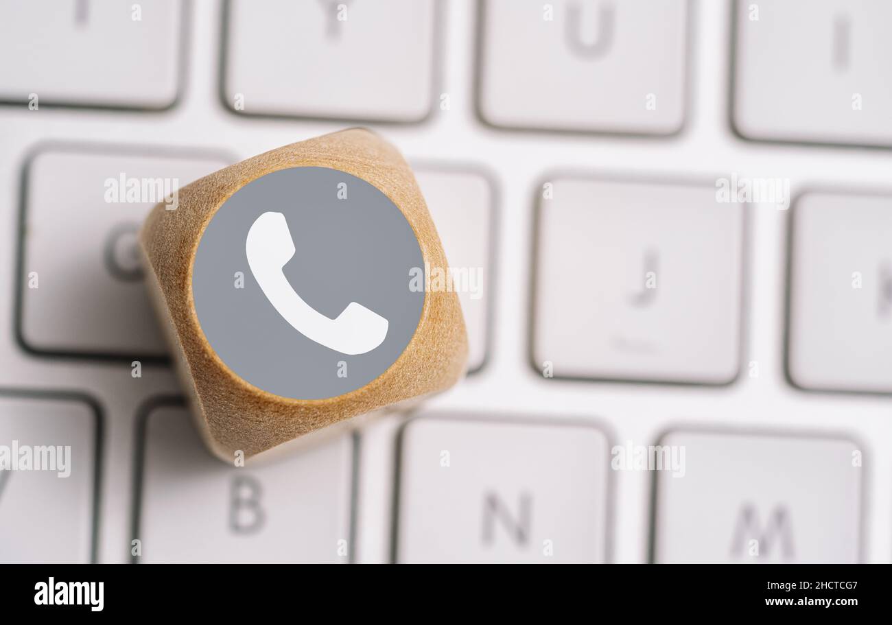 Icona del telefono su un cubo di legno su una tastiera. Immagine concettuale dei metodi di contatto e comunicazione Foto Stock