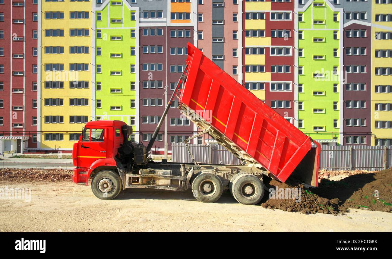 Costruire la scena urbana. Edificio a più piani casa appartamento e camion scarico terreno al giorno. Foto Stock