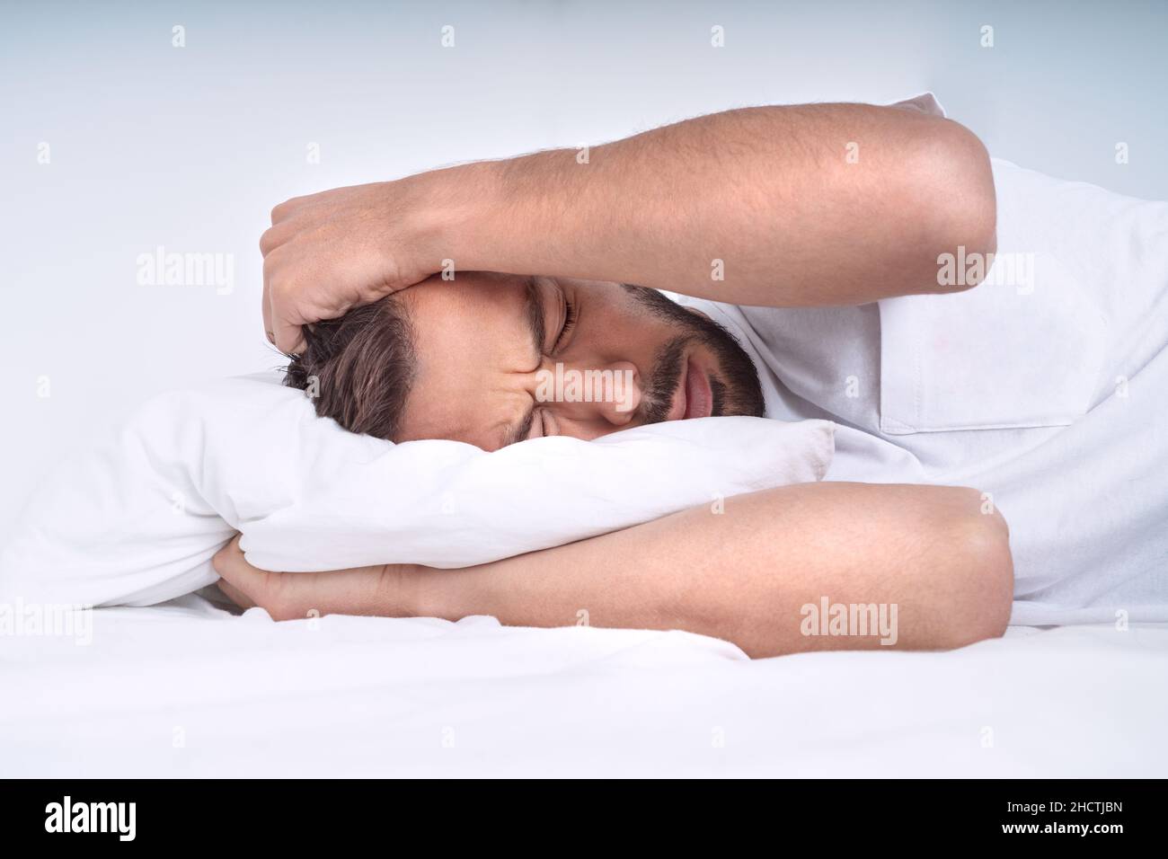 Giovane uomo con stress emotivo che sente dolore e che soffre di mal di testa tensione, emicrania o depressione Foto Stock