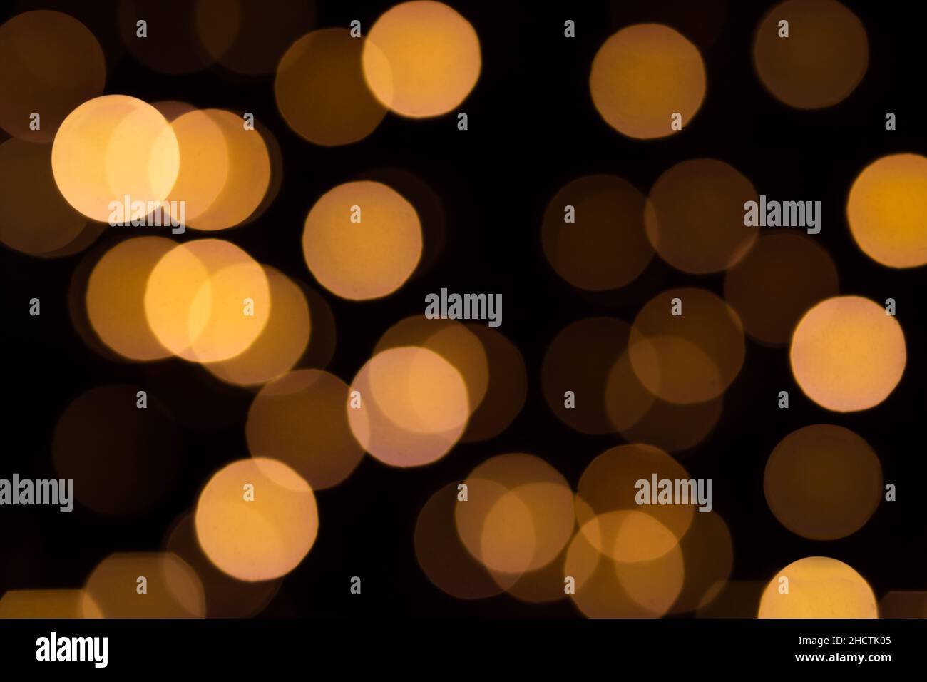 Natale e felice anno nuovo bokeh astratto luci in toni caldi arancione su sfondo nero sfocato Foto Stock