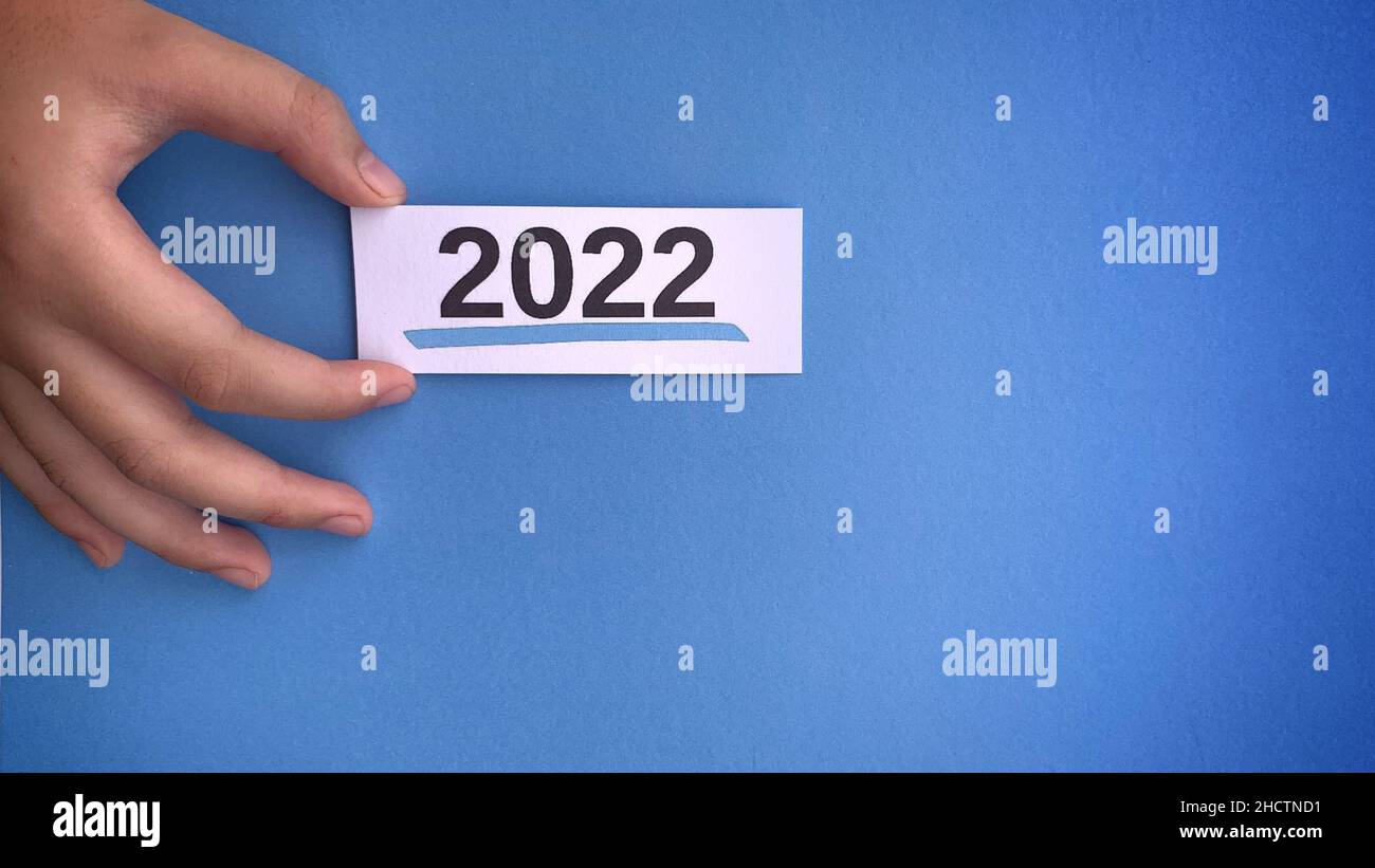 Immagine con una mano che tiene un piccolo pezzo di cartone con 2022 testo. Concetto di nuovo anno. Foto Stock