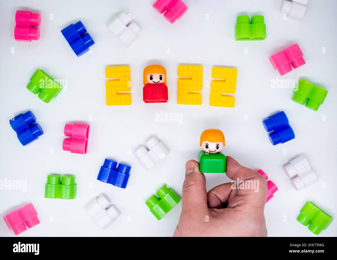 Blocchi di costruzione vintage colorati, giocattoli figure in plastica: Ragazza in 2022 numeri, ragazzo in mano, sfondo bianco. Foto Stock