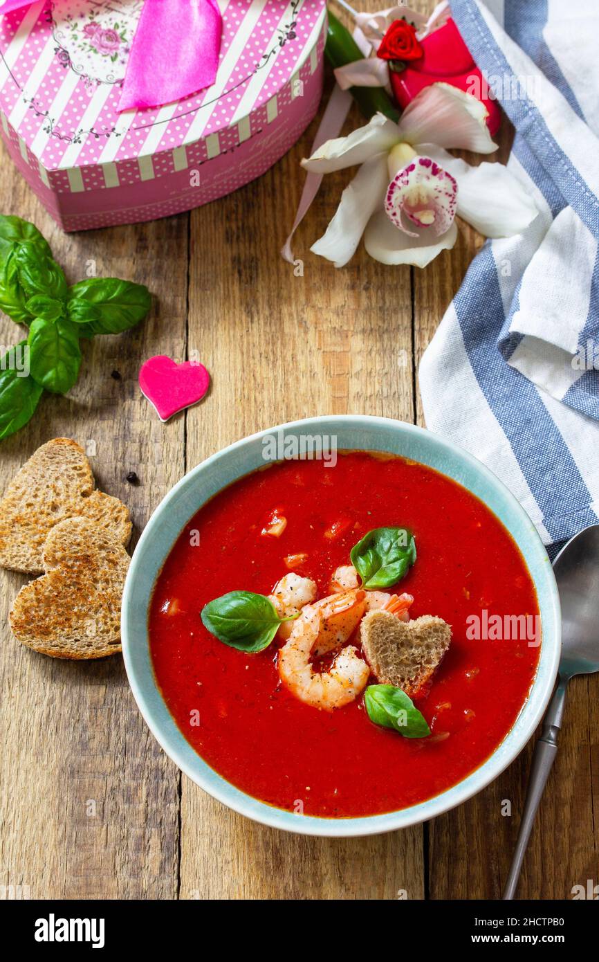 Zuppa di San Valentino fatta in casa, cibo di festa. Zuppa di pomodoro purea gazpacho con pomodori serviti a base di pesce su un rustico tavolo di legno. Foto Stock