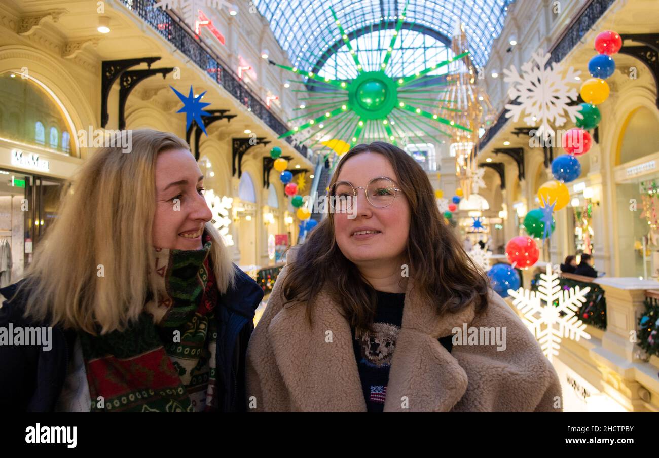 Due giovani e belle amiche al centro commerciale sorridenti, ammirano il luminoso arredamento natalizio. Foto Stock