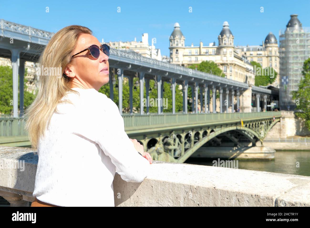 Ritratto di una donna bionda nella città di Parigi. Ponte di Bir hakeim e edificio storico sullo sfondo. Foto Stock