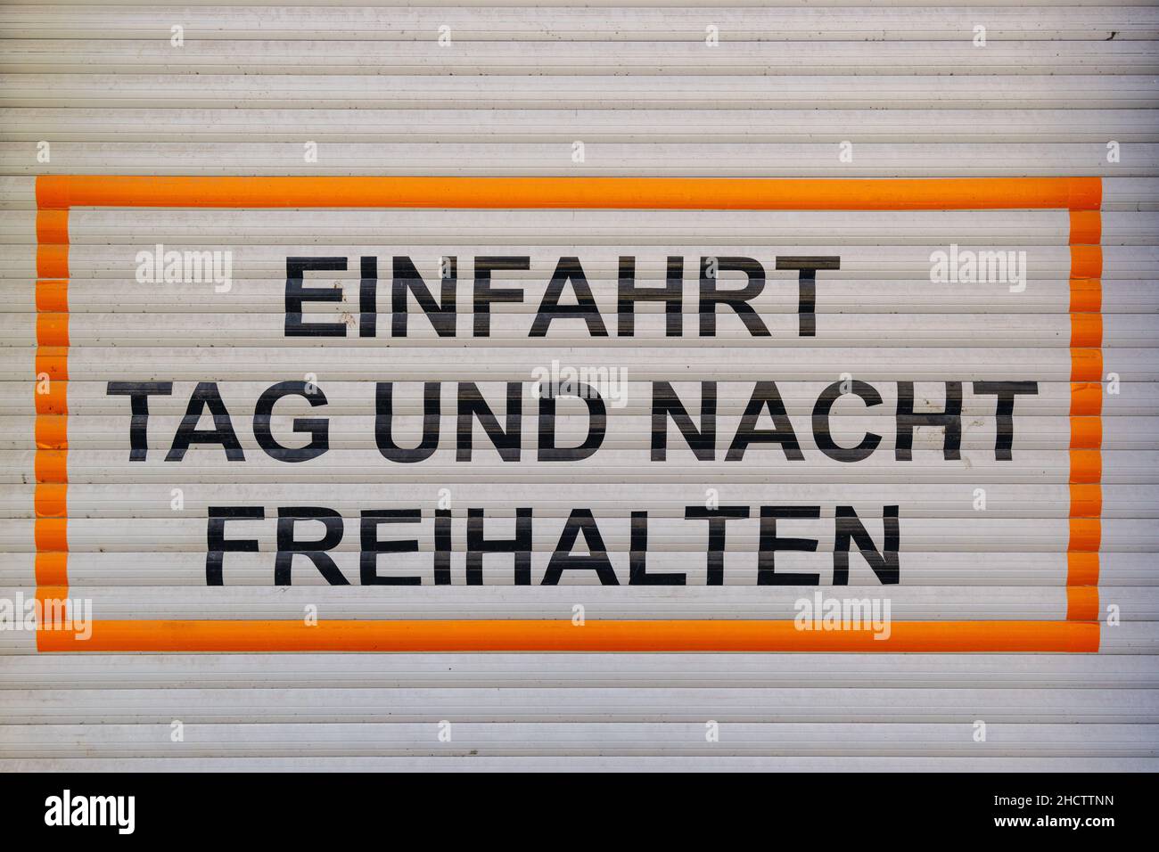 Testo tedesco Einfahrt Tag und Nacht freihalten, Traduci tenere la guida libera giorno e notte, parcheggio vietato segno su una porta garage. Foto Stock